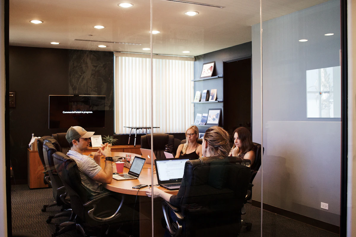 A team discussing a project around a table with laptops and presentation materials.